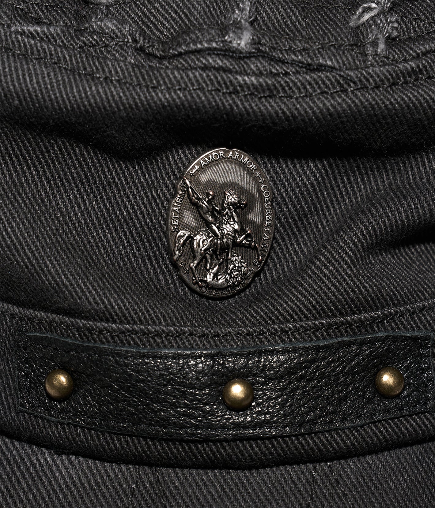 Close-up of a black leather jacket with a brand emblem and studs.