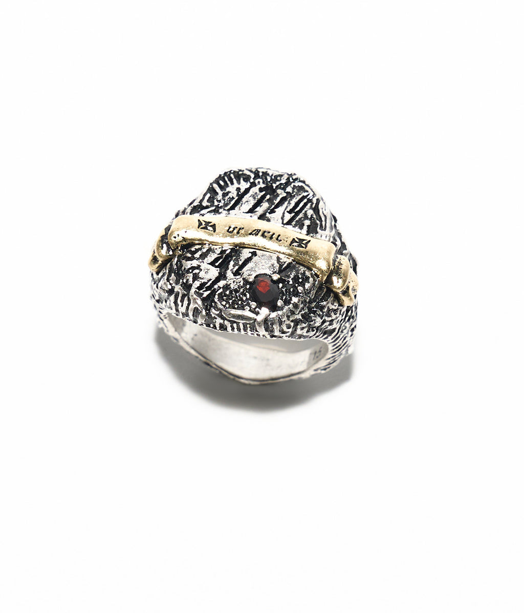 Silver ring with intricate design and red gemstone on a white background